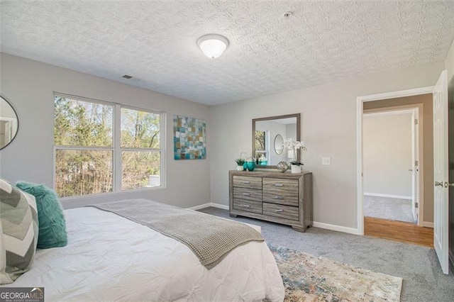 carpeted bedroom with baseboards and a textured ceiling