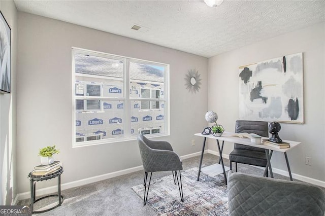 carpeted office space featuring a textured ceiling and baseboards