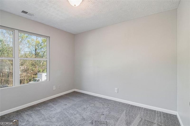 empty room with visible vents, baseboards, a textured ceiling, and carpet floors
