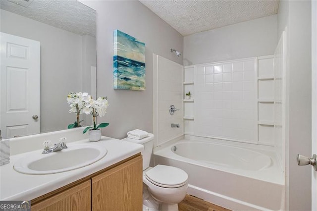 bathroom featuring vanity, a textured ceiling, toilet, and shower / washtub combination