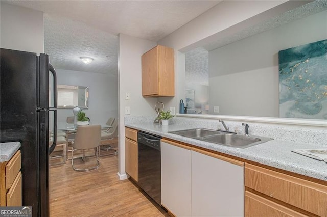 kitchen featuring light wood-style floors, a textured ceiling, black appliances, light countertops, and a sink