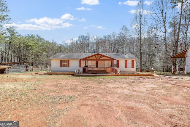 view of front facade featuring a wooded view and a wooden deck