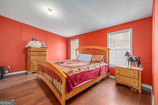 bedroom with baseboards, a textured ceiling, and wood finished floors