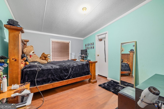 bedroom featuring lofted ceiling, a textured ceiling, and wood finished floors