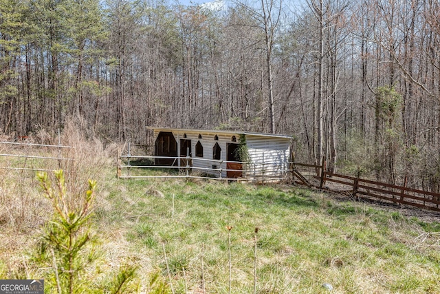 view of front of house featuring an exterior structure, a forest view, and an outdoor structure