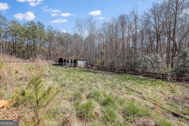 view of yard featuring an outdoor structure, fence, and a forest view