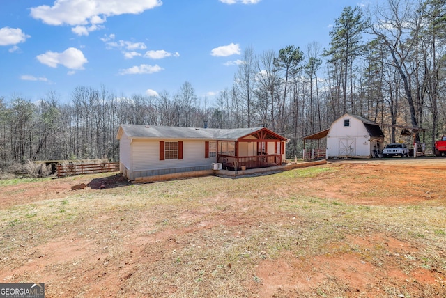 view of front of home featuring a view of trees, an outdoor structure, a front lawn, and fence