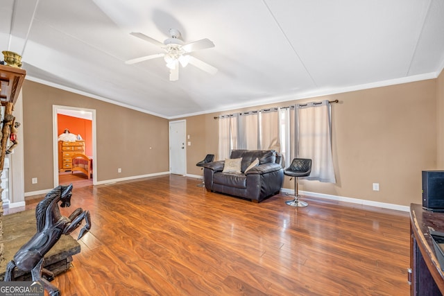 living area with ceiling fan, baseboards, wood finished floors, and crown molding