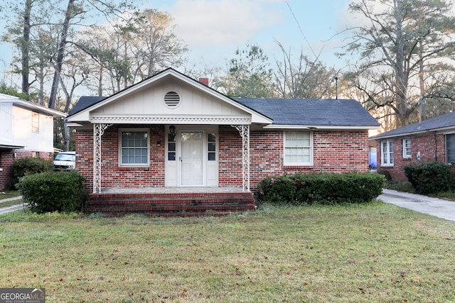 view of front of home with brick siding, covered porch, and a front lawn