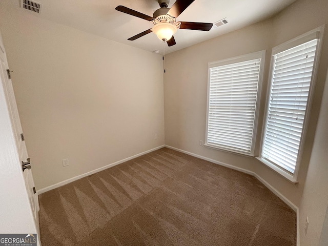 carpeted spare room featuring visible vents, baseboards, and ceiling fan