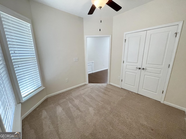 unfurnished bedroom with a closet, baseboards, carpet, and a ceiling fan