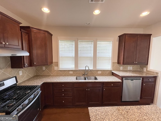 kitchen with a sink, backsplash, appliances with stainless steel finishes, and under cabinet range hood