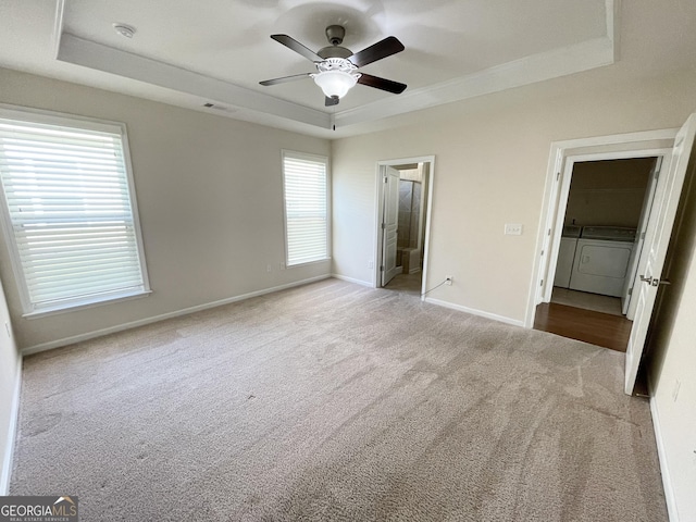 unfurnished bedroom with baseboards, a raised ceiling, carpet floors, and washing machine and dryer