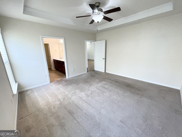 unfurnished bedroom with a tray ceiling, baseboards, light colored carpet, and ornamental molding