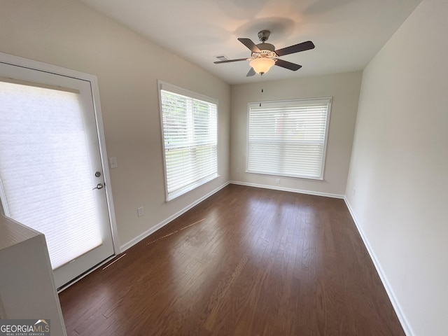 empty room with a ceiling fan, baseboards, and dark wood-style flooring