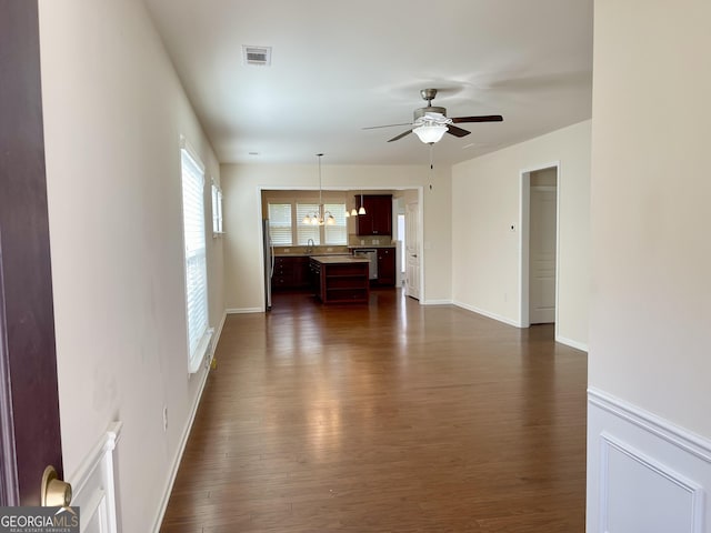 unfurnished living room with visible vents, dark wood-type flooring, a sink, baseboards, and ceiling fan