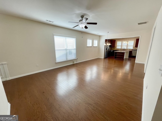 unfurnished living room featuring dark wood finished floors, visible vents, baseboards, and ceiling fan