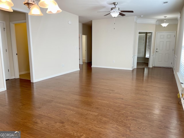 unfurnished living room featuring wood finished floors, baseboards, visible vents, crown molding, and ceiling fan with notable chandelier