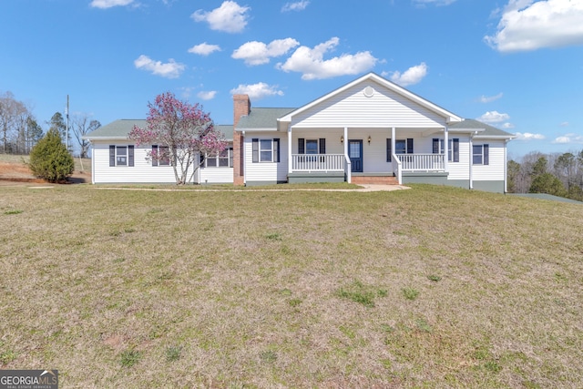 view of front of house with covered porch, a chimney, and a front lawn