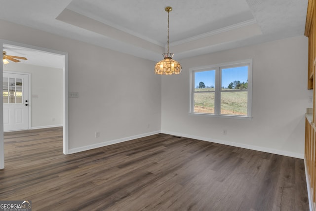 unfurnished dining area featuring baseboards, dark wood finished floors, a tray ceiling, ceiling fan, and crown molding