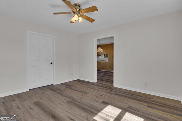 empty room with a ceiling fan, wood finished floors, and baseboards