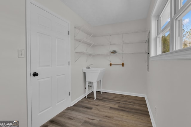 clothes washing area featuring baseboards and wood finished floors