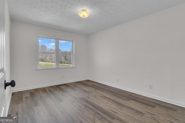 unfurnished room with baseboards, a textured ceiling, and wood finished floors