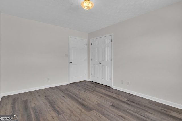 spare room featuring dark wood finished floors and baseboards