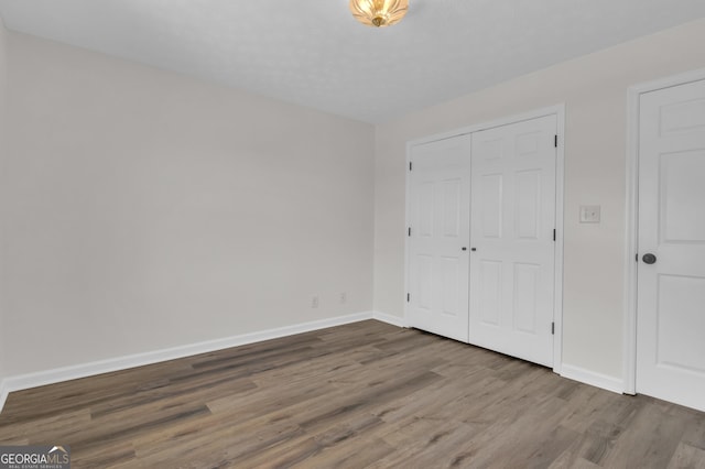 unfurnished bedroom with a closet, baseboards, and wood finished floors