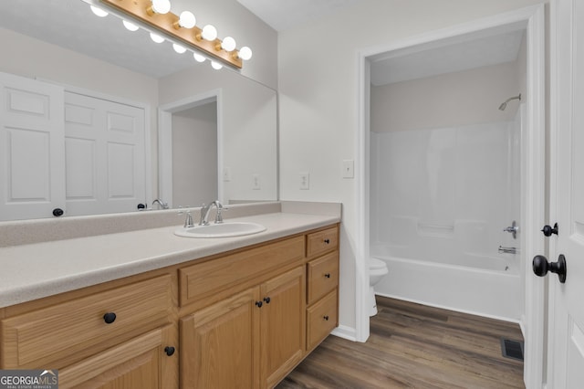 bathroom featuring vanity, wood finished floors, visible vents, toilet, and shower / bathtub combination