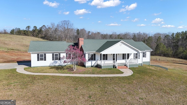 view of front of property with a chimney, a porch, and a front lawn