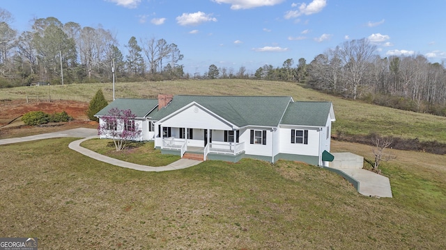 view of front facade featuring a porch, driveway, a front lawn, and roof with shingles