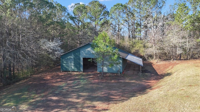 view of pole building with driveway and a view of trees