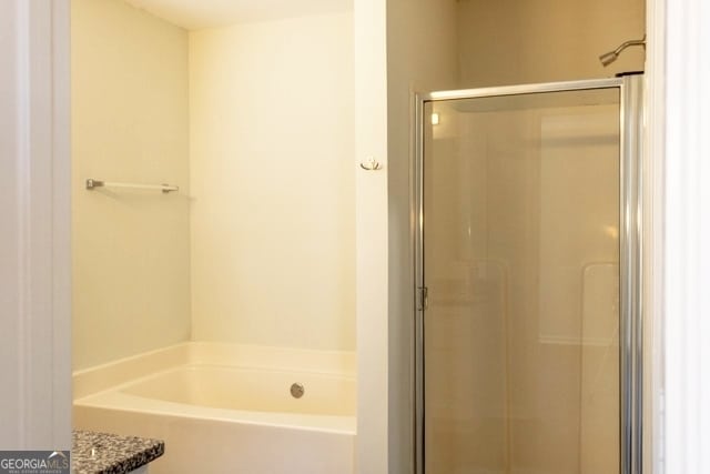 bathroom featuring a stall shower and a bath