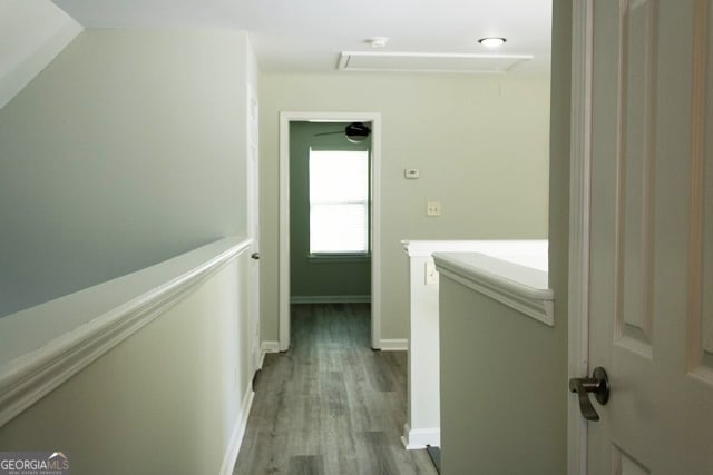 hall with baseboards, an upstairs landing, attic access, and wood finished floors