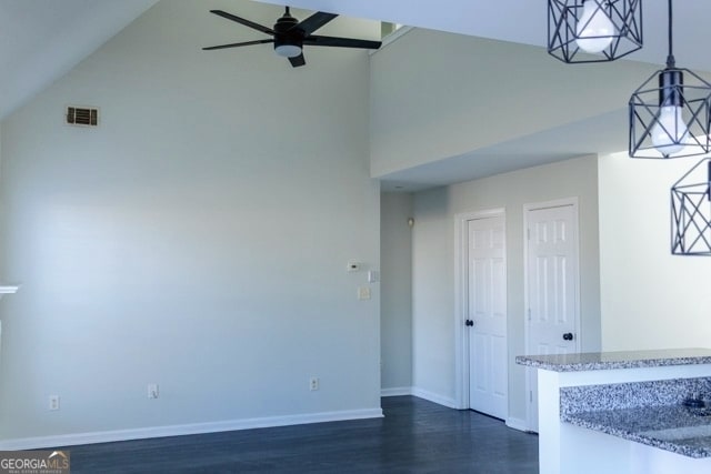 unfurnished living room featuring dark wood finished floors, a ceiling fan, visible vents, and high vaulted ceiling