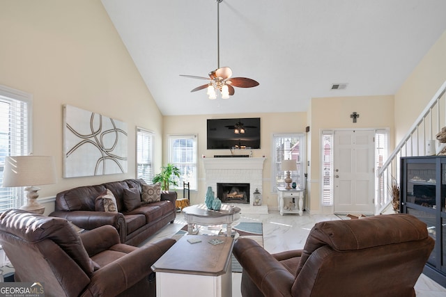 living room with a wealth of natural light, marble finish floor, a fireplace, and ceiling fan