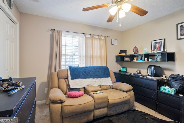 carpeted office space featuring baseboards, a textured ceiling, and ceiling fan