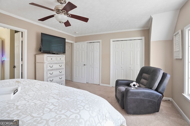 bedroom featuring crown molding, ceiling fan, baseboards, multiple closets, and light carpet