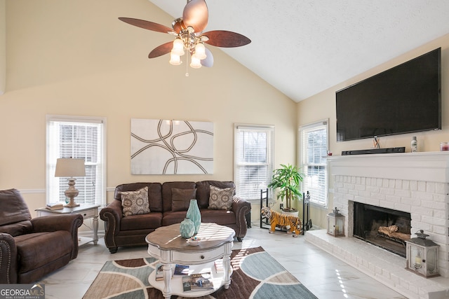 living room featuring high vaulted ceiling, ceiling fan, a fireplace, and a textured ceiling