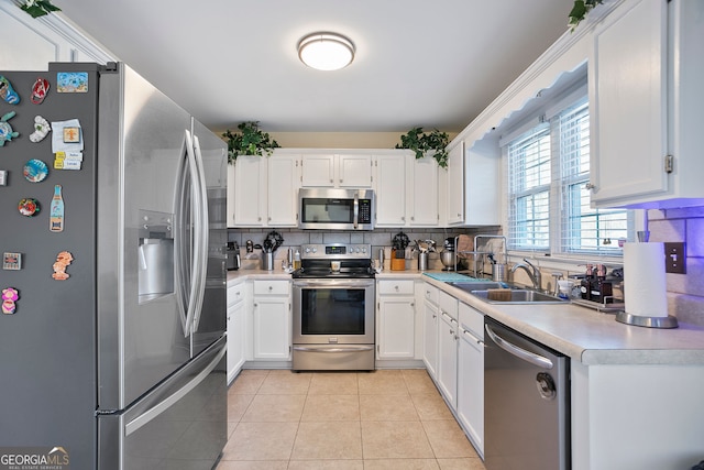 kitchen with light tile patterned flooring, a sink, decorative backsplash, light countertops, and stainless steel appliances