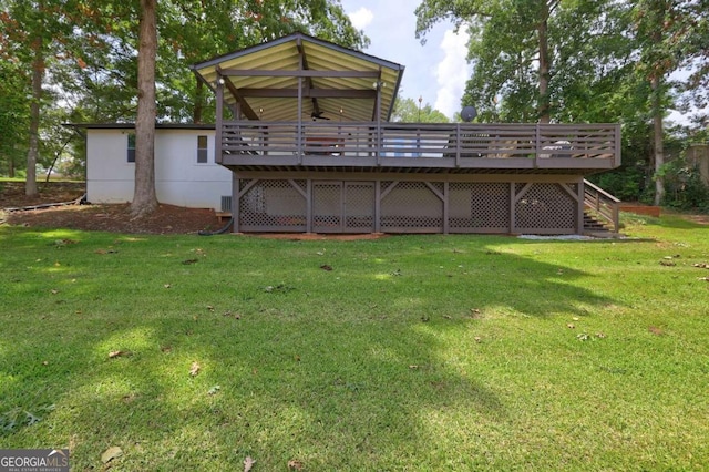 back of house with a lawn, a ceiling fan, a wooden deck, and stairs