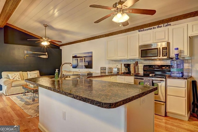 kitchen with ceiling fan, appliances with stainless steel finishes, dark countertops, a sink, and white cabinetry