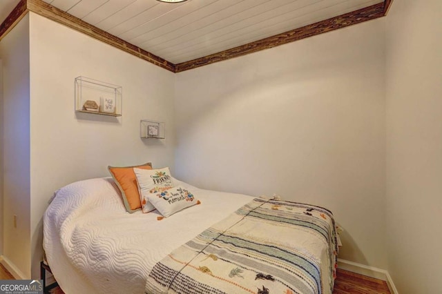 bedroom with crown molding, wood ceiling, baseboards, and wood finished floors