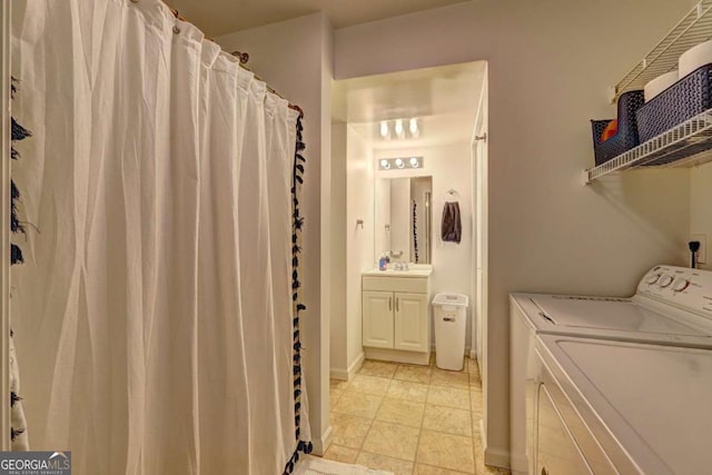 clothes washing area with washing machine and clothes dryer, laundry area, baseboards, and a sink