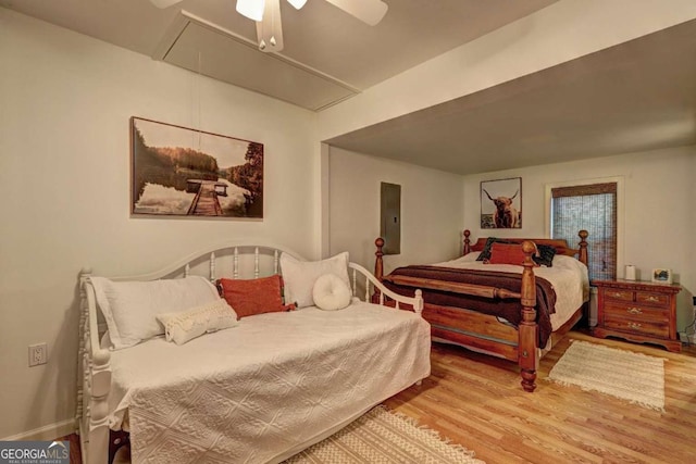 bedroom featuring a ceiling fan, attic access, and wood finished floors