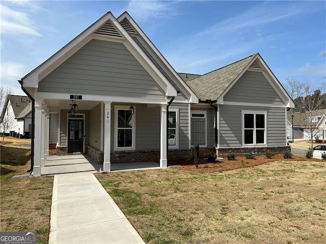 view of front facade with brick siding, a porch, and a front yard