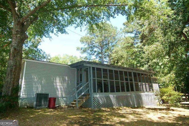 rear view of property with central AC unit and a sunroom