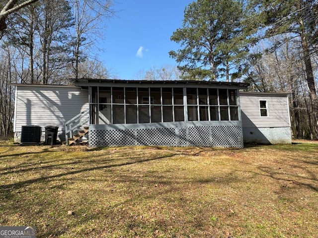 rear view of house featuring central air condition unit, a lawn, and a sunroom