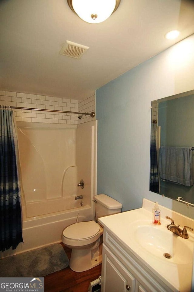 full bath featuring visible vents, shower / tub combo with curtain, toilet, wood finished floors, and vanity